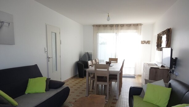 A living room with a sofa, a dining table, and a television.