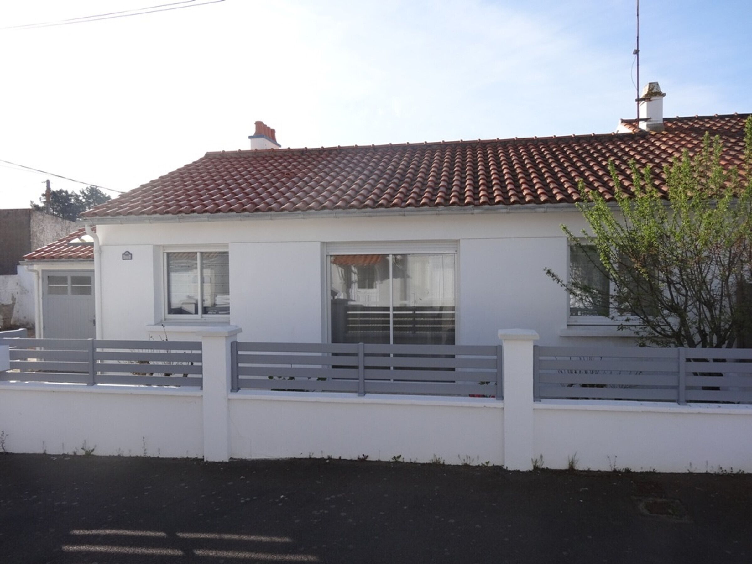 A single-story house with a tiled roof, a white exterior, and a small porch with a white railing.