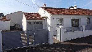 A single-story house with a red-tiled roof, a white exterior, and a grey gate.