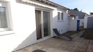 A house with a patio, two lounge chairs, and a sliding glass door.