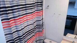 Une salle de bain avec un rideau de douche à rayures, des toilettes et un lavabo avec un miroir.