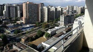 Un quartier urbain dense, avec de nombreux immeubles d’habitation, un ciel dégagé et des montagnes à l’horizon.