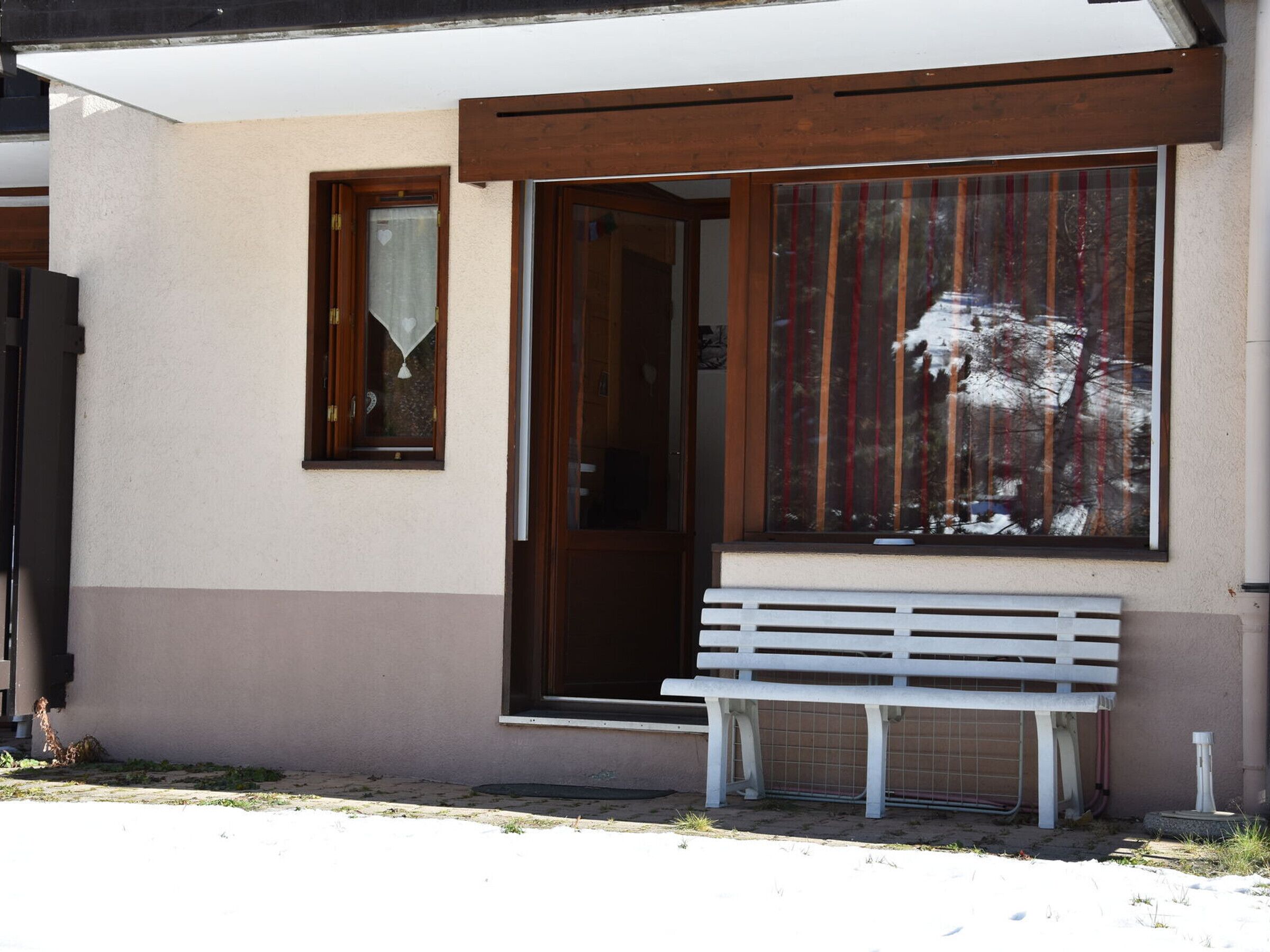 A building with a large window, a bench outside, and a door.