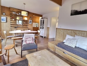 Um quarto aconchegante com uma mesa de jantar de madeira, cadeiras, um sofá e uma cama.