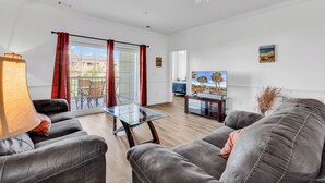 Een moderne woonkamer met een glazen salontafel, leren banken en een televisie.
