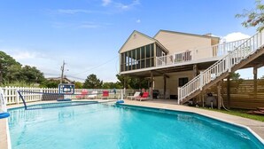 A swimming pool with a house in the background, a covered deck, and a white fence. - It's All Good | 780 ft from the beach | Private Pool, Dog Friendly, Hot Tub (Virginia Beach)