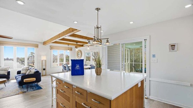A spacious kitchen with wooden cabinets, a central island, and a large window providing a view. - It's All Good | 780 ft from the beach | Private Pool, Dog Friendly, Hot Tub (Virginia Beach)