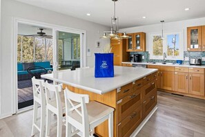 A modern kitchen with a large island, wooden cabinets, and a view to an outdoor patio.