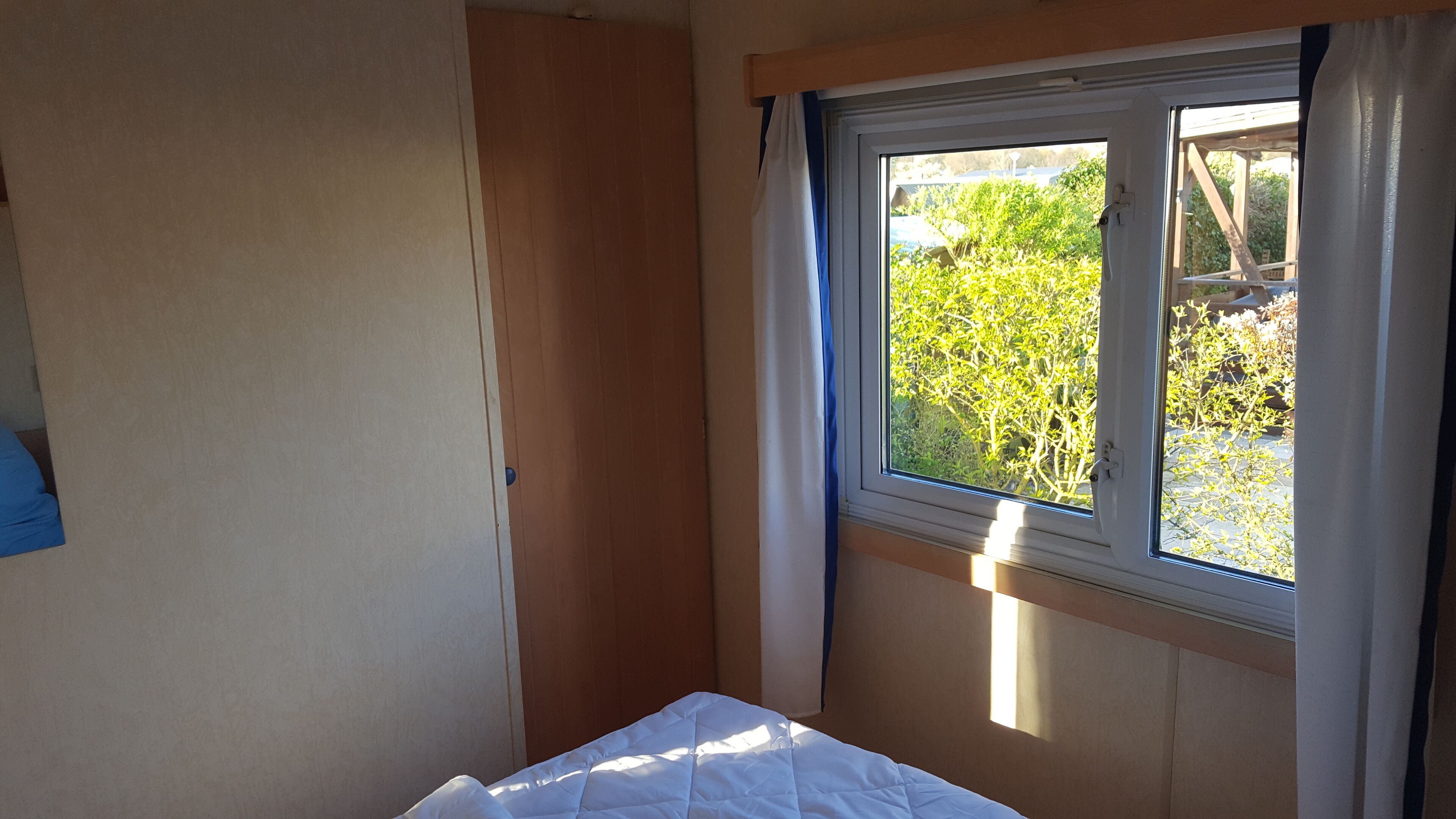 Ein kleines Zimmer mit einem Einzelbett und einem Fenster mit Blick auf einen Garten.