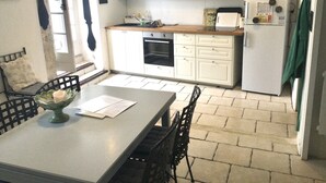 A compact kitchen with white cabinets, a microwave, and a stove. There is a dining table with chairs and a vase on it.