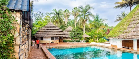 Una piscina al aire libre, sombrillas, sillones reclinables de piscina