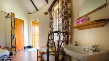 A bathroom with a white sink, wooden door, patterned curtains, and a mirror above the sink.