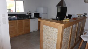 Eine moderne Küche mit Holzausstattung, einer eingebauten Mikrowelle und einer zentralen Kochinsel mit Barhocker.
