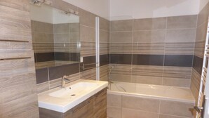 Ein modernes Badezimmer mit Waschbecken, Spiegel und Badewanne.