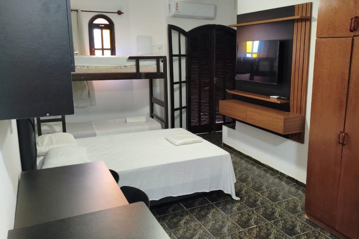 A room with a bunk bed, a television mounted on a wooden cabinet, and a wardrobe.