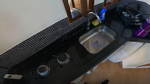 Cozinha com bancada preta, pia de aço inoxidável e fogão a gás.