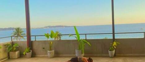 Clase de yoga en la azotea con vistas al mar.