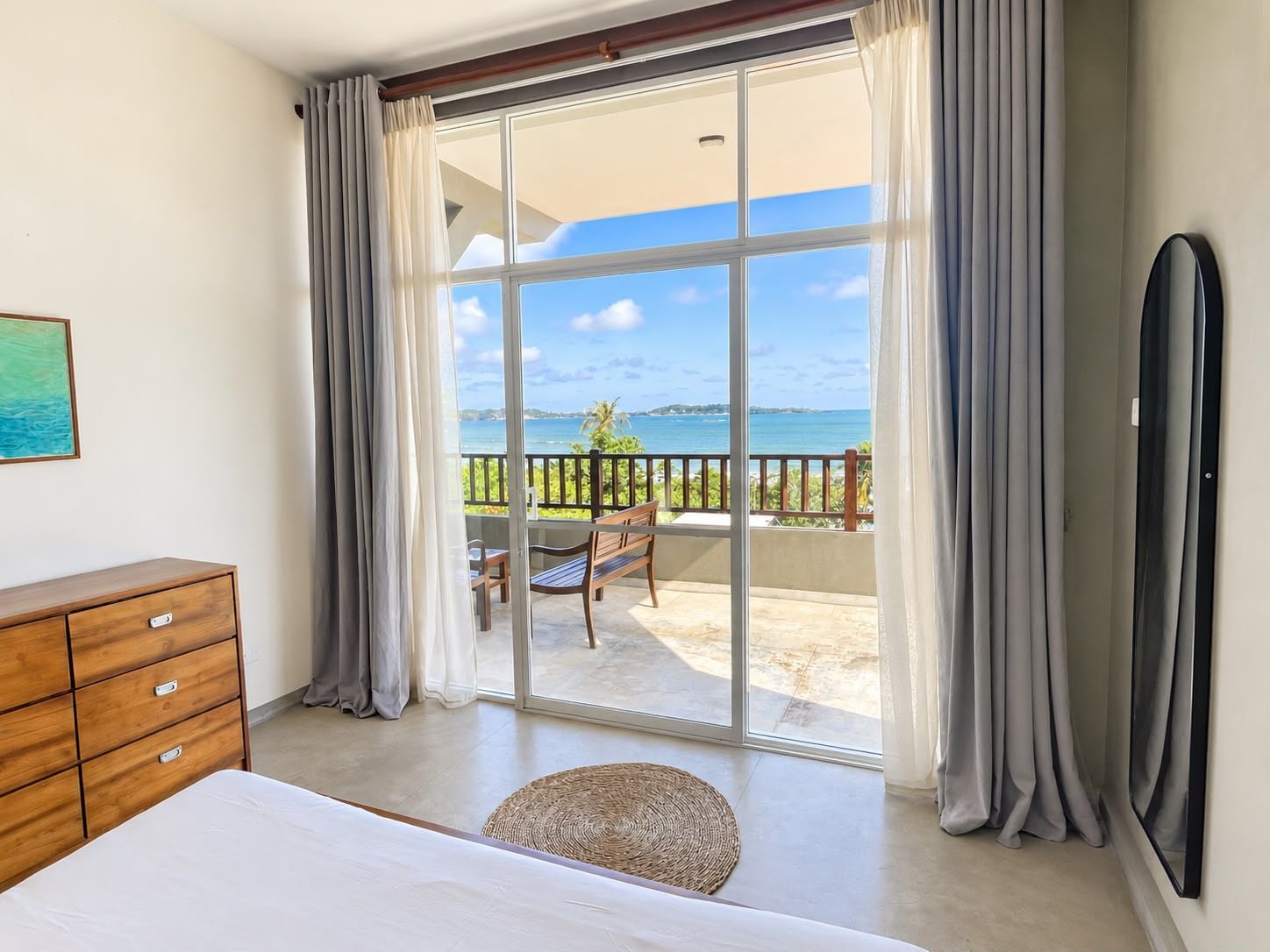 Een slaapkamer met een grote schuifglazen deur die leidt naar een balkon met uitzicht op de oceaan.
