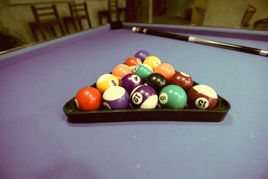 A pool table with a set of billiard balls arranged in a triangle formation.