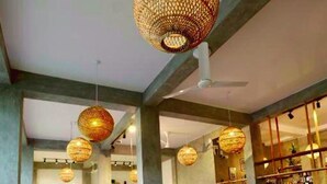 A room with a pool table, wicker chairs, and hanging wicker lamps.
