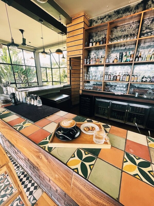 A bar area with a tiled counter, a coffee cup, and a tray with cookies and a glass.