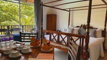 A four-poster bed with a wooden frame, a dining table with plates and cups, and a menu.