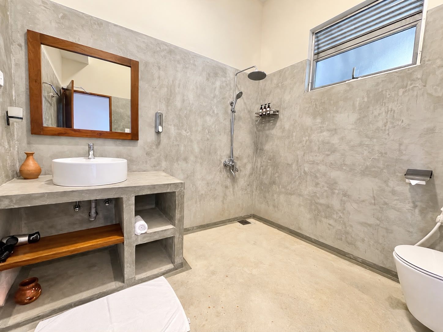 A modern bathroom with a white sink, a mirror, a shower, and a toilet.