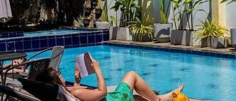 Una piscina al aire libre, sillones reclinables de piscina