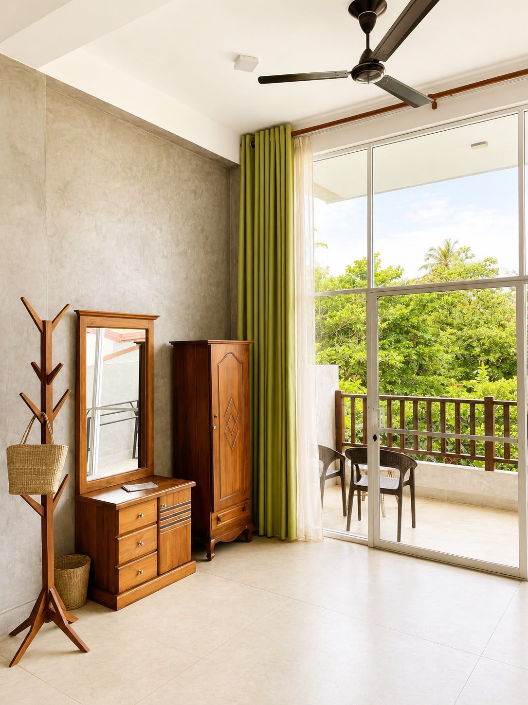 A room with a large sliding glass door leading to a balcony, a ceiling fan, and a wooden cabinet with drawers.