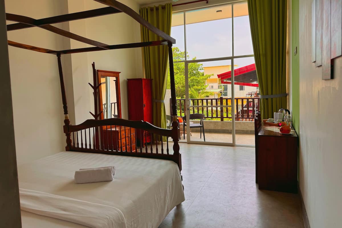 A four-poster bed in a room with a view of a balcony and outdoor furniture.