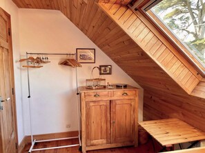 A wooden cabinet with drawers and a small table, a coat rack with hangers, and a picture on the wall. - Idyllic house in Trébéron close to the sea B0018 (Crozon)