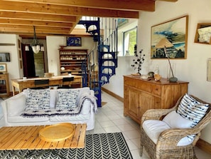 A cozy living room with a sofa, a wicker chair, a wooden cabinet, and a staircase. - Idyllic house in Trébéron close to the sea B0018 (Crozon)