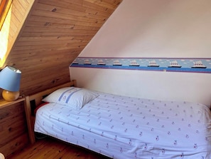 A single bed with a patterned bedspread, a bedside lamp, and a wall with a nautical-themed border. - Idyllic house in Trébéron close to the sea B0018 (Crozon)