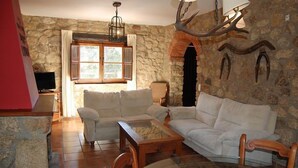 Ein gemütliches Wohnzimmer mit Steinwänden, einem Kamin und einem großen Fenster.