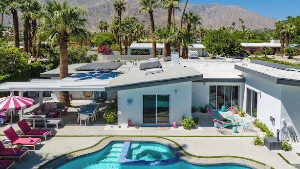 A modern pool area with a hot tub, lounge chairs, and a view of mountains.