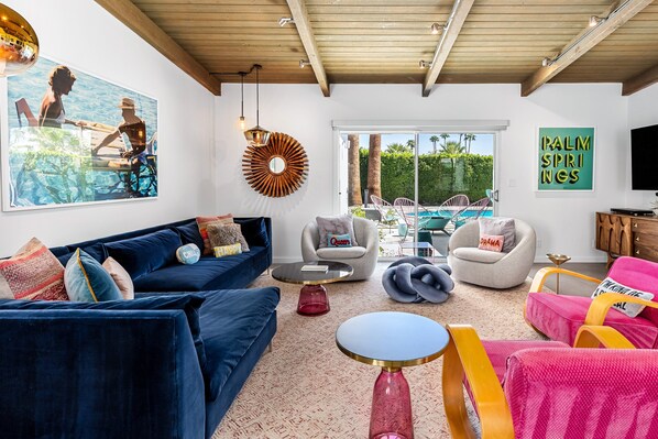 A living room with a blue sofa, a round coffee table, and a pink chair.