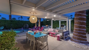 An outdoor patio with a pool, seating area, and a grill.