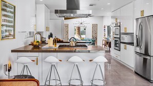 A modern kitchen with a central island, stainless steel appliances, and bar stools.