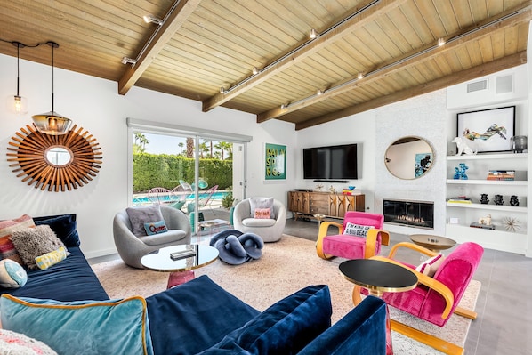 Uma sala de estar moderna com vista para a piscina, uma lareira e uma televisão.