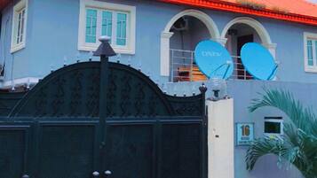 Une maison avec un toit rouge, une entrée fermée par un portail et des antennes paraboliques.