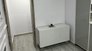 Ein Eckzimmer mit einem weißen Schrank, einem kleinen Topfpflanzen und einem Spiegel an der Wand.