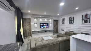 Ein modernes Wohnzimmer mit einer großen Eckcouch, einem flachbildfernseher an der Wand und einem weißen Konsolentisch.
