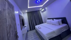 Ein modernes Hotelzimmer mit einem Bett, einem Fernseher, einem Schreibtisch und einer Deckenleuchte.