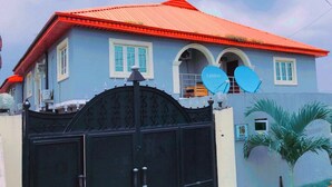 A house with a red roof, a black gate, and a satellite dish. - Volantis Gold (Lagos)