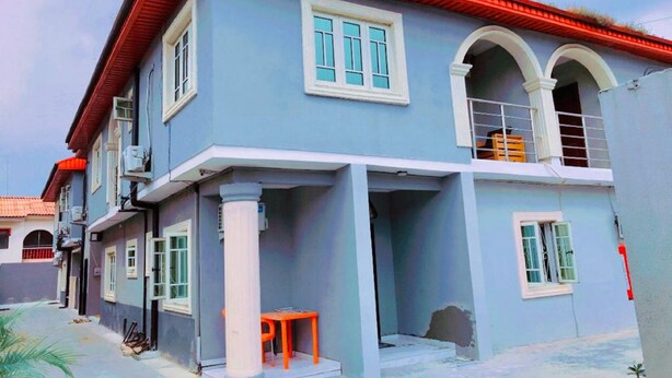 A two-story building with a red roof, white-framed windows, and a balcony. - Volantis Gold (Lagos)