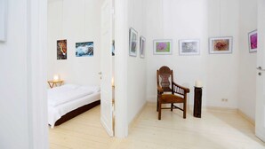 A room with a bed, a chair, and several framed pictures on the wall. - Seminar & vacation apartment - Gutshaus Bartelshagen (Dalkendorf)