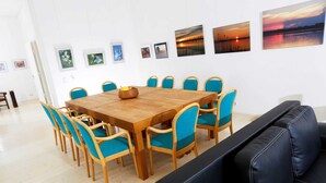 A dining area with a wooden table and blue chairs, surrounded by artwork on the walls. - Seminar & vacation apartment - Gutshaus Bartelshagen (Dalkendorf)