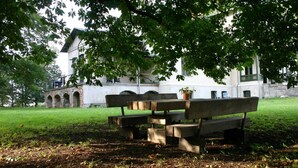 A picnic table with benches in a park area with a building in the background. - Seminar & vacation apartment - Gutshaus Bartelshagen (Dalkendorf)