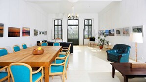 A spacious room with a long wooden table and blue chairs, large windows, and artwork on the walls. - Seminar & vacation apartment - Gutshaus Bartelshagen (Dalkendorf)