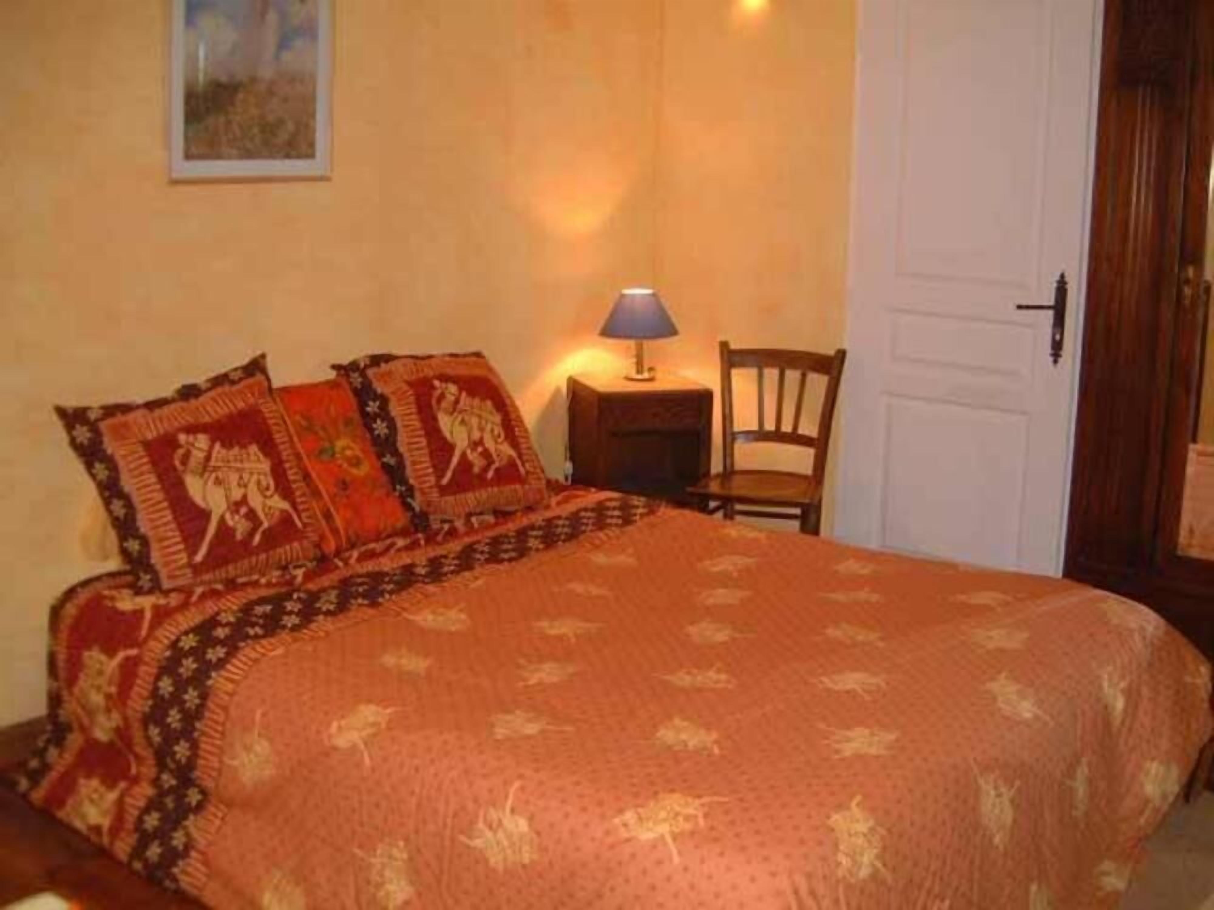 A bedroom with a bed, a nightstand, a chair, and a door.